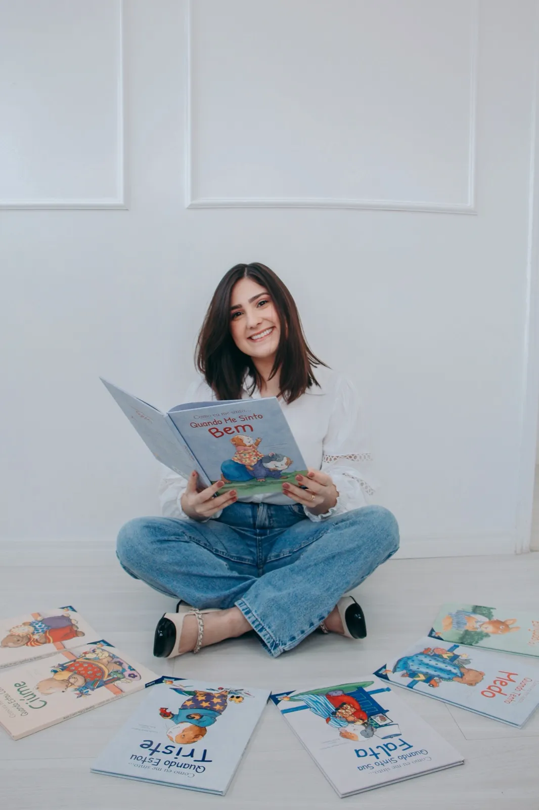 Bruna Rocha sorrindo enquanto folheia um livro sobre emoções