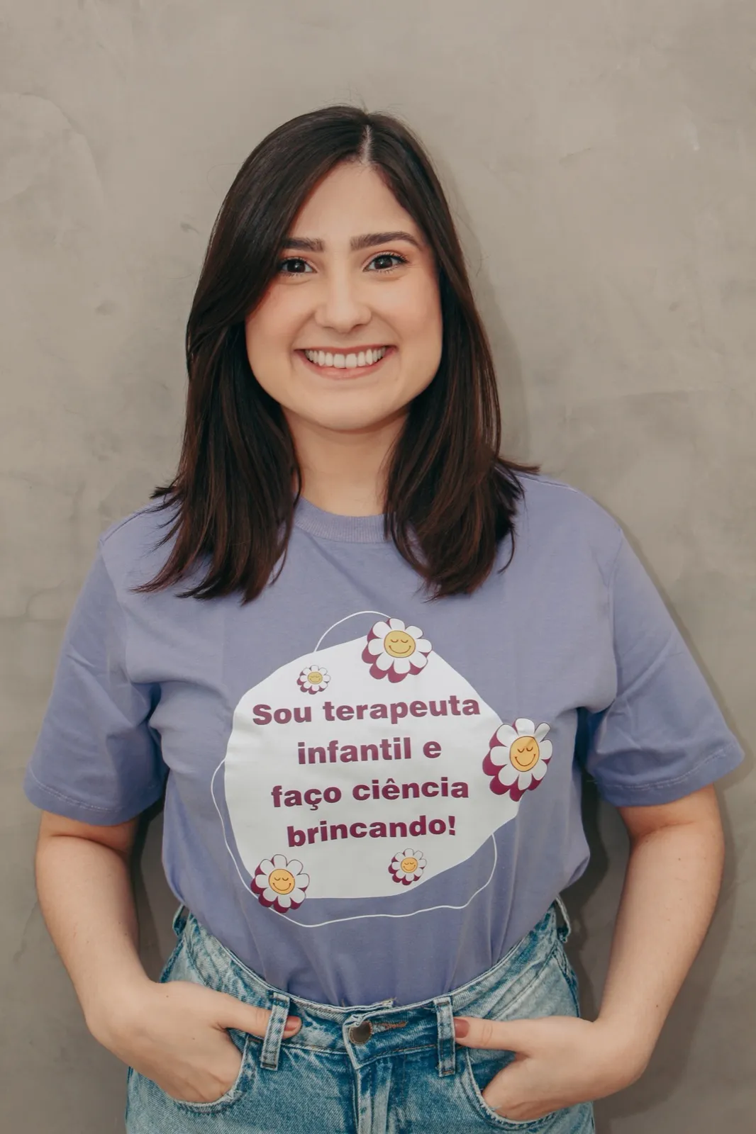 Bruna Rocha sorrindo, com a camiseta 'Sou terapeuta infantil e faço ciência brincando!'
